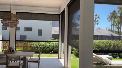 Exterior screens lowered across a covered lanai beside the pool